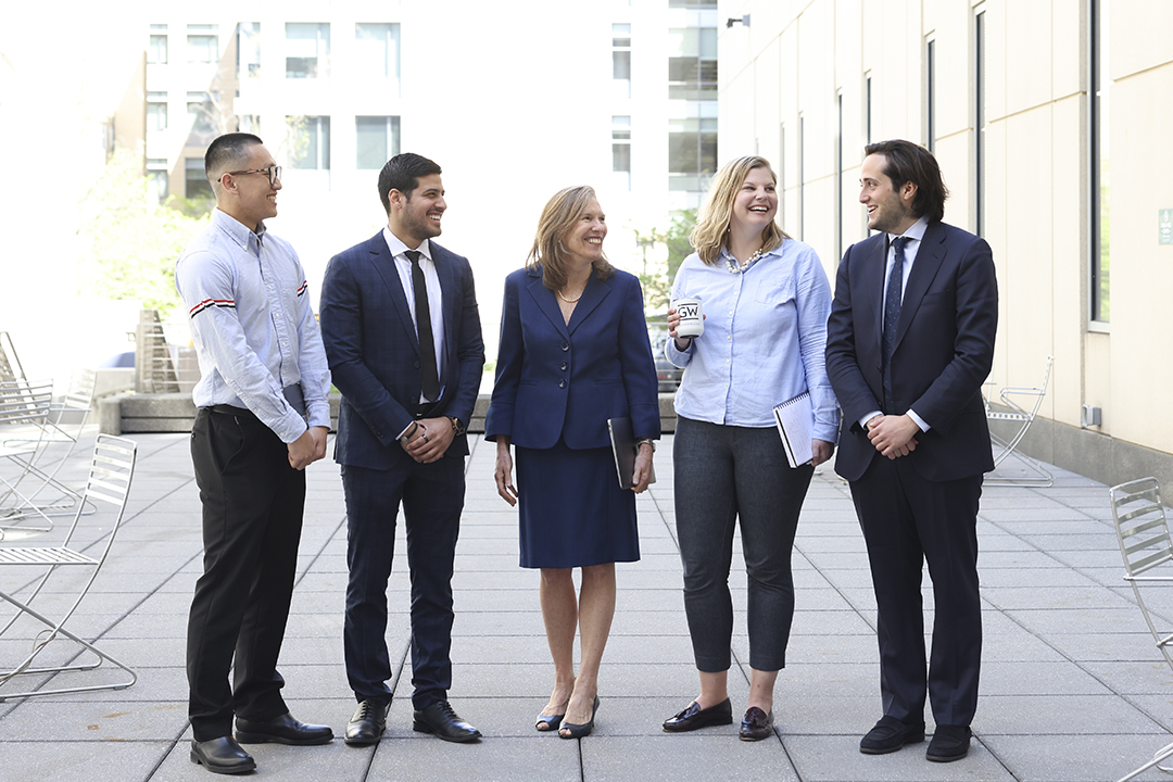 Four GWSB sport management students chat in a courtyard outside Duques Hall with Professor Lisa Delpy Neirotti