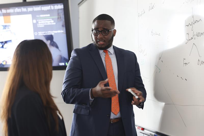 GWSB Global MBA students chat in front of a whiteboard in 2022